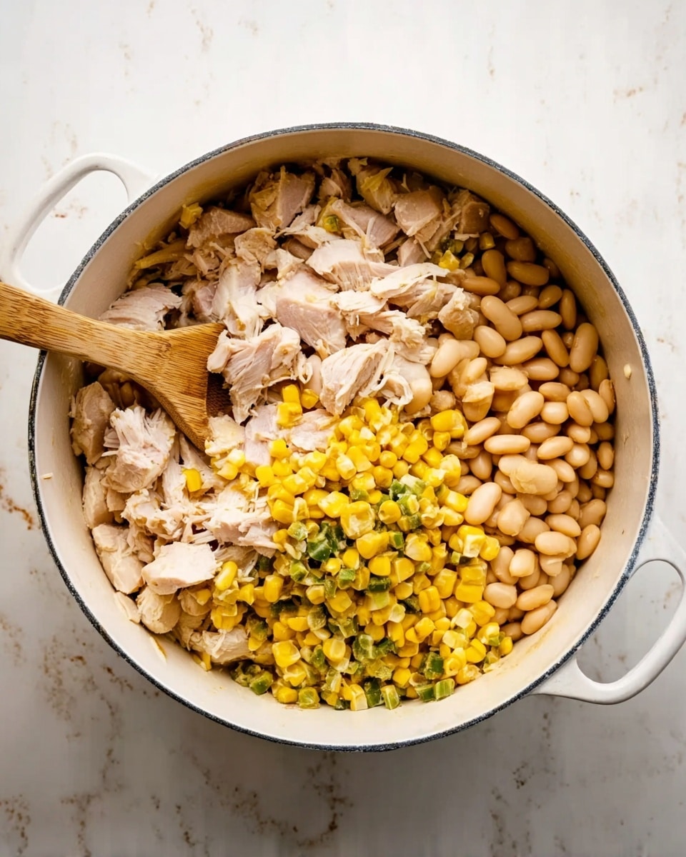 A white round pot filled with three main layers: a large pile of light beige beans on the right side, a heap of yellow corn mixed with small green pieces at the bottom, and a generous amount of chopped pale pink cooked chicken pieces on the left side. A wooden spoon with a smooth texture rests diagonally on top of the pot, partly covered by the chicken and corn. The pot sits on a white marbled surface. photo taken with an iphone --ar 4:5 --v 7