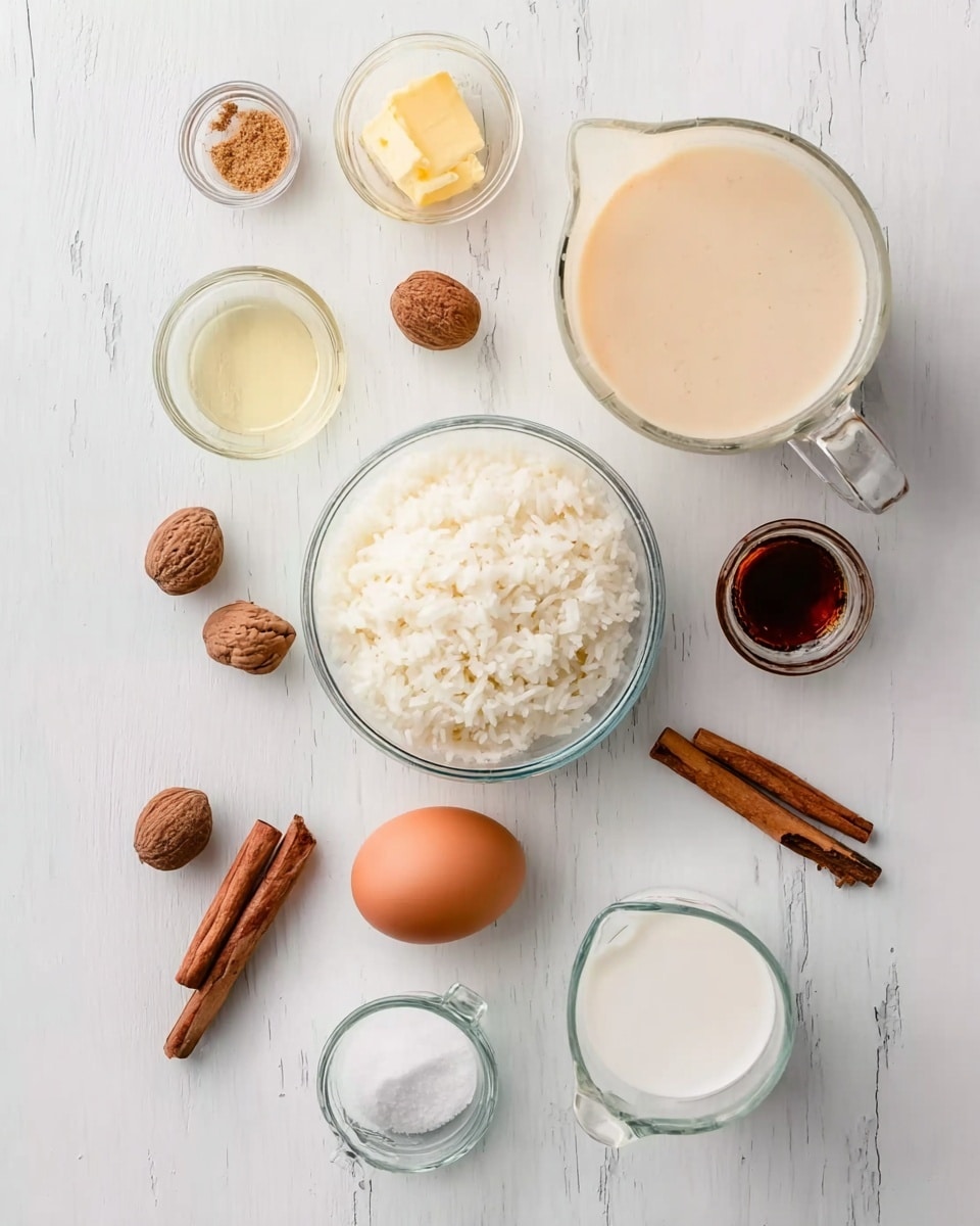 A white marbled surface holds a clear glass bowl of white cooked rice in the center, surrounded by small glass containers holding various ingredients: a clear liquid, a small amount of yellow butter, and white sugar. A clear glass measuring jug filled with a creamy beige liquid sits near the top right, while another clear measuring jug with a white liquid is placed near the bottom left. Whole nutmegs and two cinnamon sticks are placed near the rice bowl, with a brown egg positioned next to the nutmegs. A small glass container with vanilla extract sits in front of the egg, and a tiny bowl with a brown spice lies near the top left. Photo taken with an iphone --ar 4:5 --v 7