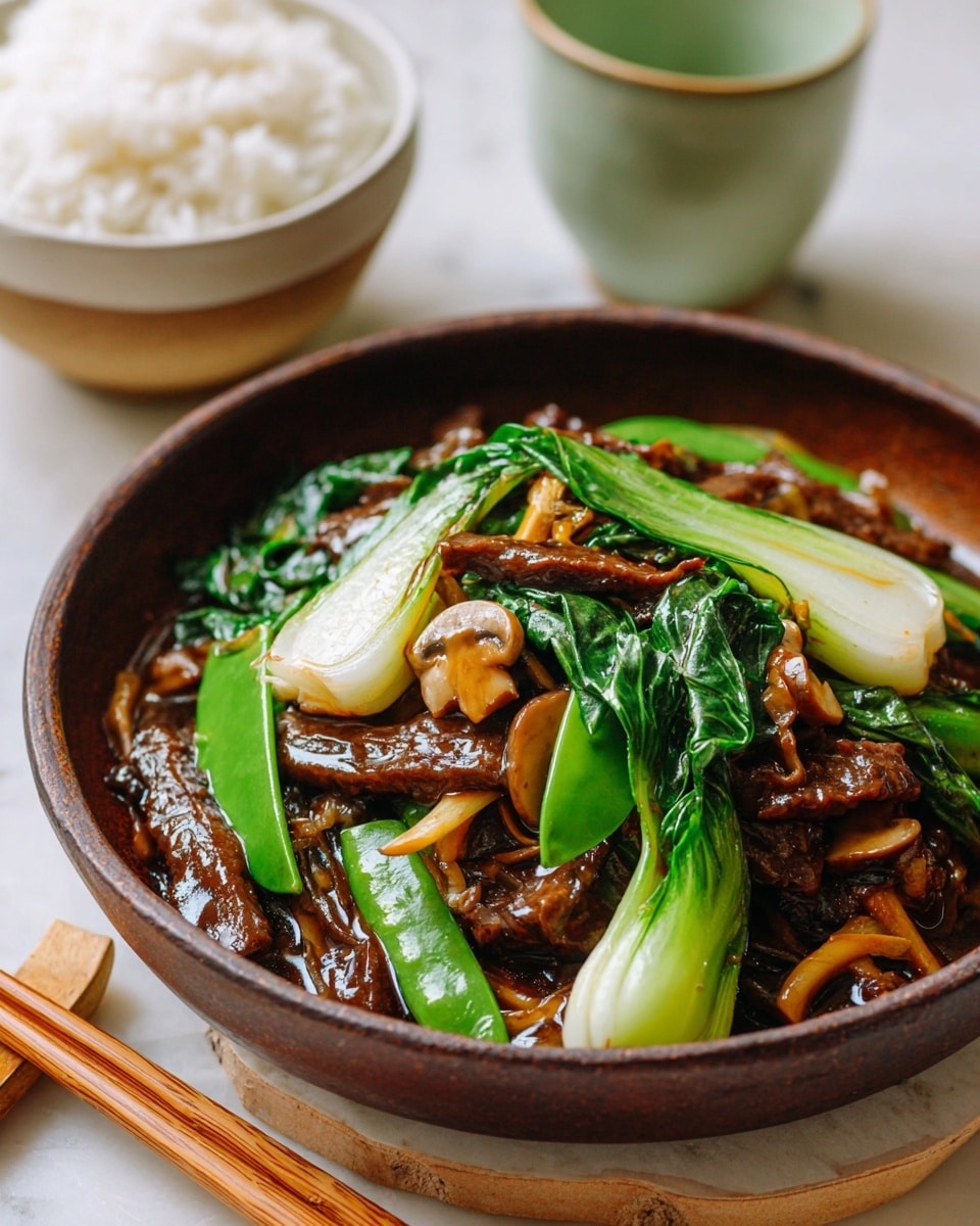 A dark brown bowl sits on a white marbled texture with wooden chopsticks resting nearby. Inside the bowl, there is a stir-fry dish with several layers: at the bottom, glossy dark brown sauce covers thin slices of meat that are also dark brown and shiny. On top of the meat, there are bright green snap peas and wilted leafy greens adding a fresh look. White slices of bok choy with a slightly translucent texture and small light brown mushrooms are mixed evenly throughout. In the background, a white bowl filled with plain white rice and a pale green cup are slightly out of focus. The overall scene is bright with natural light, showing the fresh colors and shiny textures of the food clearly photo taken with an iphone --ar 4:5 --v 7