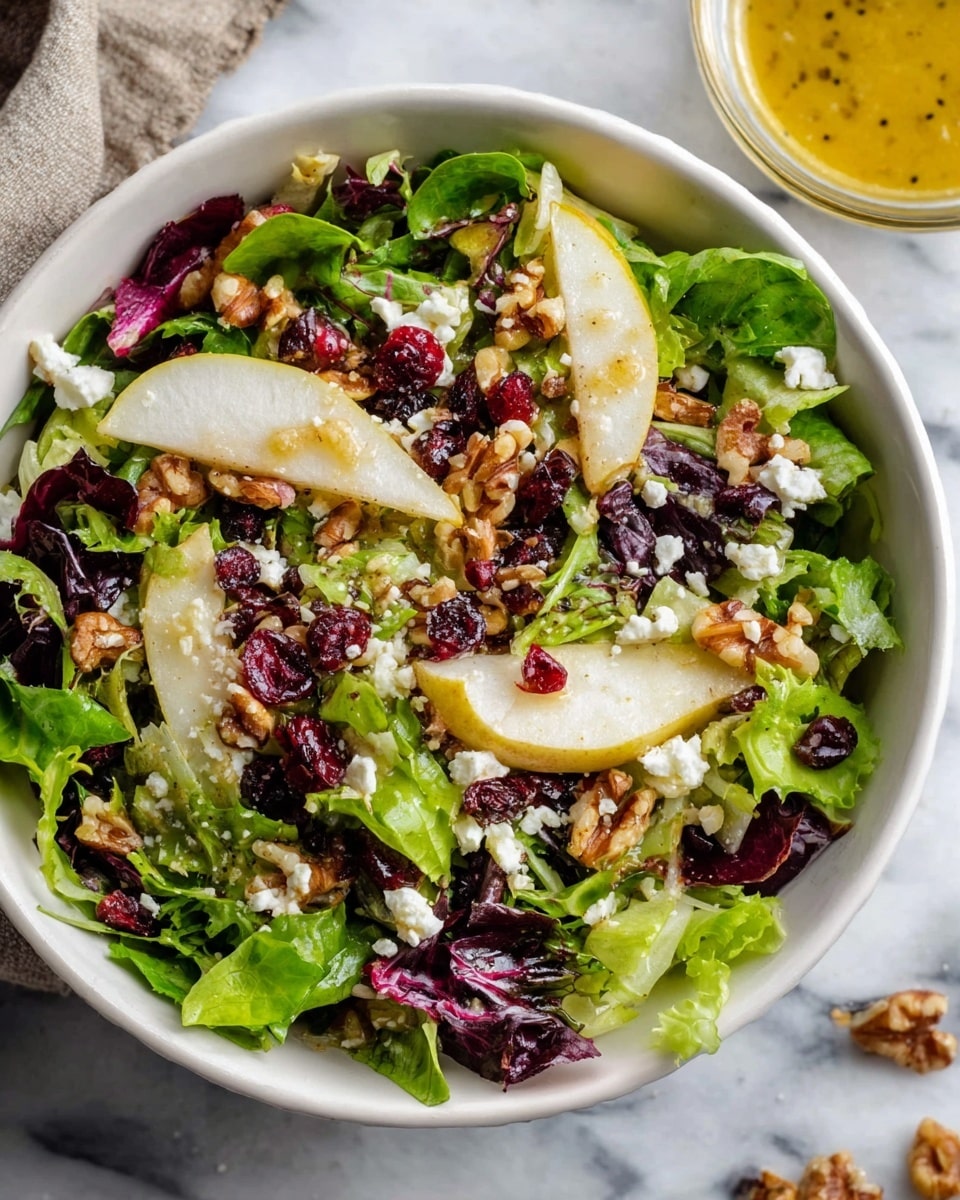 A white bowl filled with a fresh salad showing a mix of green and purple leafy lettuce as the bottom layer. On top are thin white slices of pear scattered evenly, along with small white crumbles of cheese. Bright red dried cranberries dot the salad, adding color contrast, while small pieces of light brown walnuts are spread throughout. The bowl sits on a white marbled surface with a small glass bowl of yellow mustard dressing blurred in the background. photo taken with an iphone --ar 4:5 --v 7