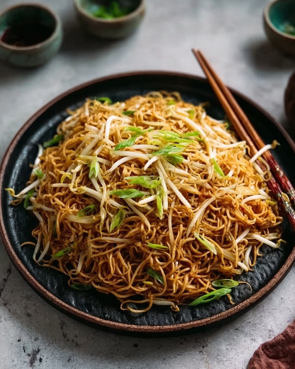 A large round dark plate filled with a single layer of thin stir-fried noodles that are light brown and slightly shiny, mixed with scattered light beige bean sprouts and thin green onion strips on top. The plate is placed on a white marbled surface with wooden chopsticks resting on the right side of the plate. There are small cups and bowls blurred softly in the background. Photo taken with an iphone --ar 4:5 --v 7