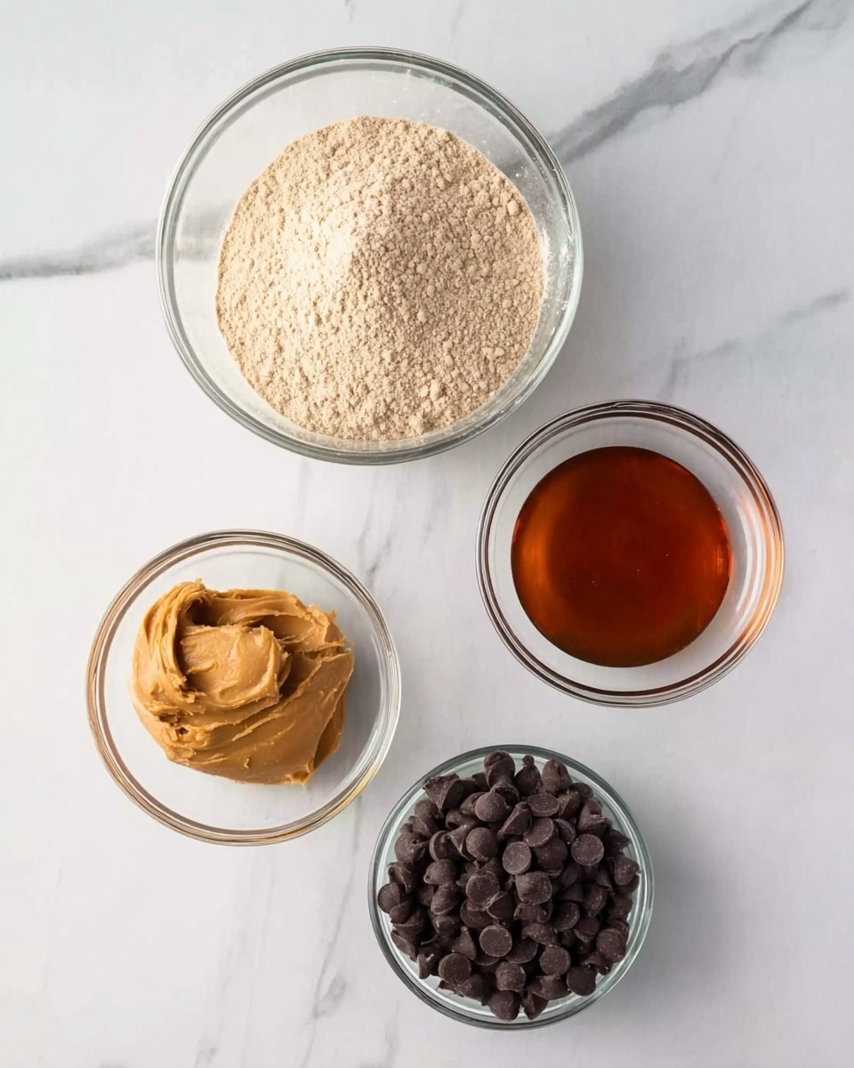 The image shows four clear glass bowls placed on a white marbled surface. The largest bowl at the top contains a light beige powdery mix. Below it, on the left, is a slightly smaller bowl filled with smooth light brown peanut butter. To the right of the peanut butter bowl, there is a small bowl holding a dark amber liquid, likely syrup. Next to it on the far right is a similarly sized bowl filled with dark chocolate chips. The setting looks clean and organized, suggesting preparation for baking or cooking, photo taken with an iphone --ar 4:5 --v 7