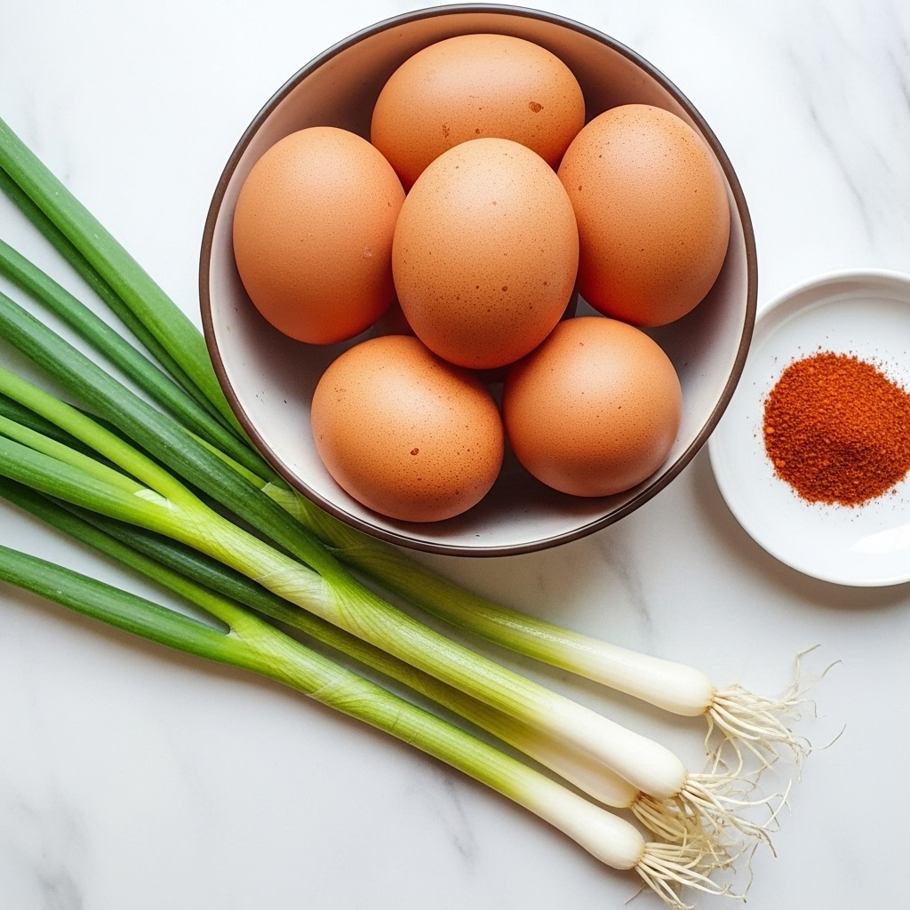 A bowl filled with six brown eggs sits on a white marbled surface, their smooth shells slightly speckled and rounded in shape. Next to the bowl, several fresh green onions lie diagonally, showing their long green stalks and white bulb ends with fine roots. In the corner, a small white plate holds a tiny pile of red spice, adding a pop of color to the scene. The setting is clean and bright, highlighting the natural colors and textures of the ingredients. photo taken with an iphone --ar 4:5 --v 7