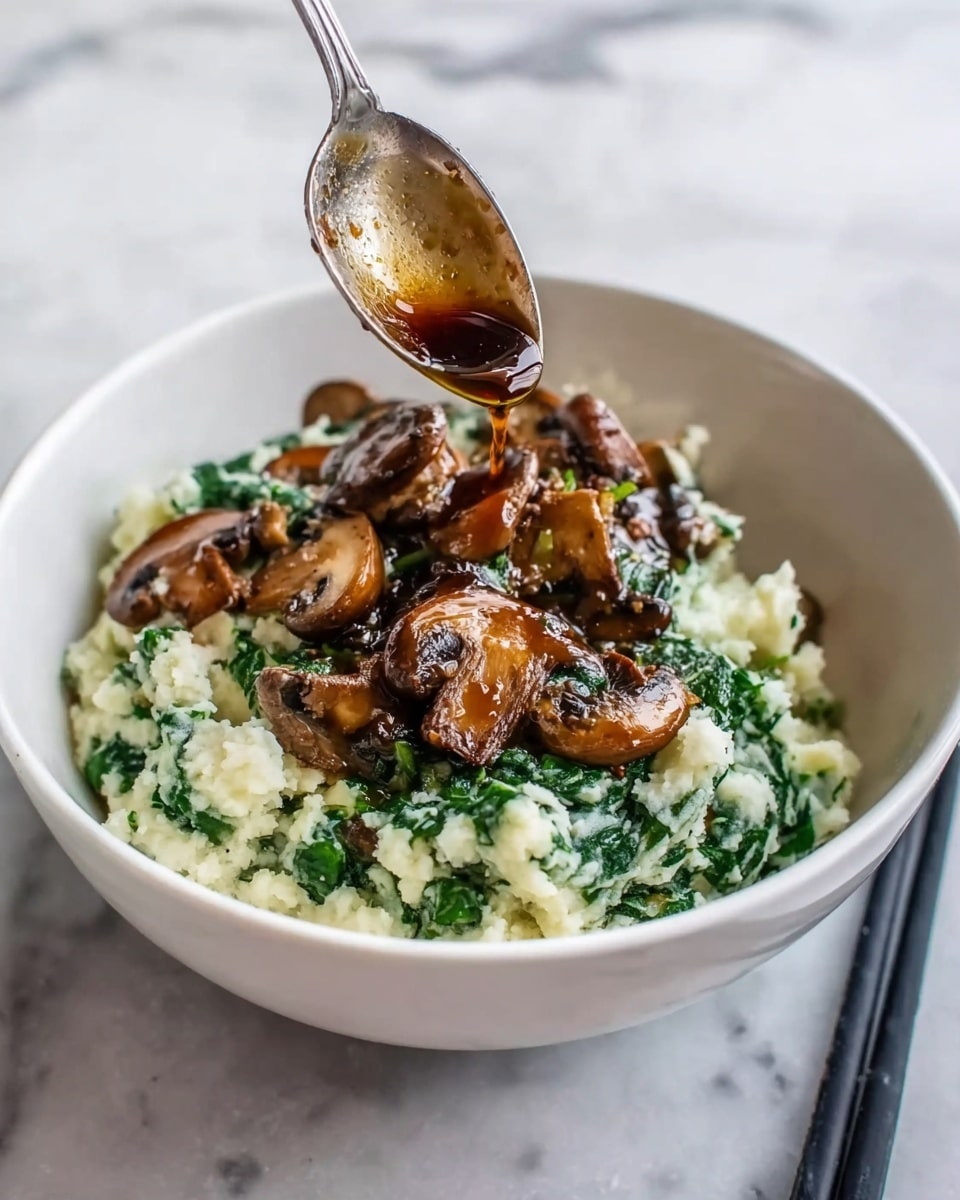 This image shows a white bowl filled with a creamy mashed mix of white potatoes and green spinach, giving the bottom layer a soft, chunky texture with bright green and white colors mixed closely together. On top of this base layer, there are scattered slices of cooked brown mushrooms with a glossy look, adding a rich, slightly shiny texture and deep brown color over the mashed potatoes and spinach. Above the mushrooms, a spoon held by a woman's hand is pouring a dark brown sauce over the food, creating a small pool of sauce on the mushrooms. The bowl sits on a white marbled surface, and a black chopstick lies next to the bowl on the right side. photo taken with an iphone --ar 4:5 --v 7
