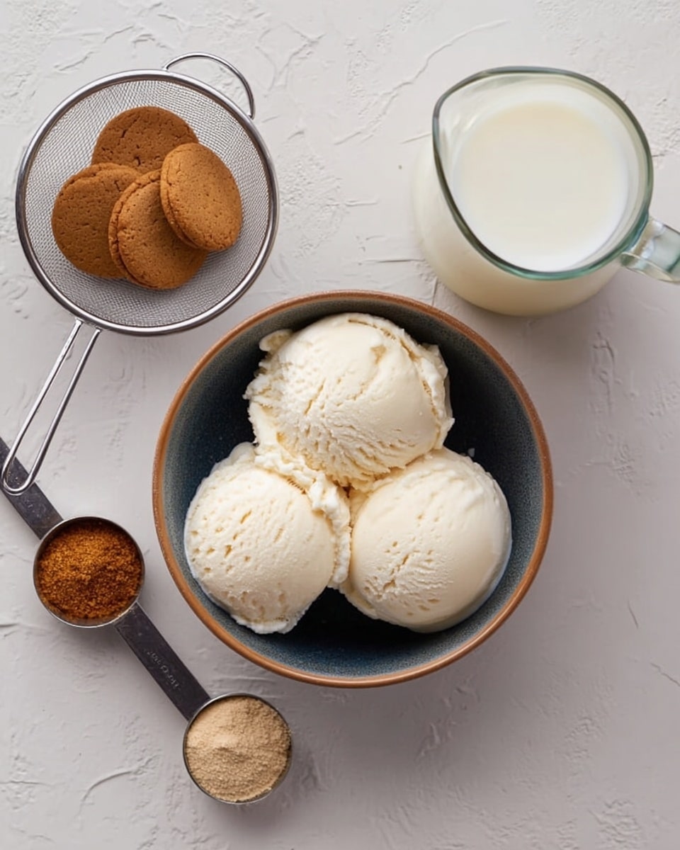 The image shows a bowl filled with three white scoops of ice cream with a smooth, creamy texture, placed in the center on a white marbled surface. To the left, there is a small metal sieve containing round brown cookies, next to two measuring spoons filled with ground spices; one is a dark brown powder and the other is a light beige powder. On the right side, a clear glass pitcher is filled with white milk, adding a soft contrast to the scene. The overall colors are neutral and warm, with a clean and simple arrangement. Photo taken with an iphone --ar 4:5 --v 7