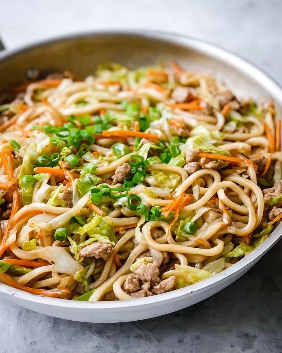 A white wok filled with stir-fried noodles mixed with small pieces of cooked light brown meat, thin strips of orange carrots, light green cabbage, and finely chopped bright green onions scattered on top. The noodles are thick and pale, twisting through the vegetables and meat, all cooked evenly with light sauce coating. The background shows a white marbled surface. photo taken with an iphone --ar 4:5 --v 7