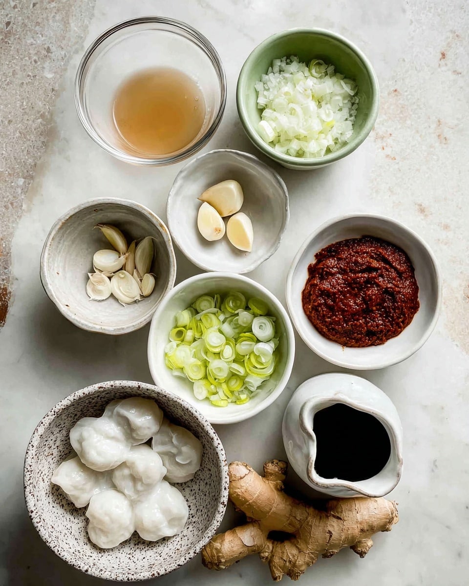 The image shows a top view of several small bowls with different ingredients arranged neatly on a white marbled surface. There is a bowl of white dumplings at the bottom left in a speckled bowl. Above it, a clear bowl contains a light brown liquid. To the upper right, a greenish bowl holds finely chopped white onions. Next to it is a small white bowl filled with a dark thick reddish paste. Near the center, a white bowl has sliced green onions, and above it another white bowl contains three peeled cloves of garlic. A small white ceramic jug holds a dark liquid at the bottom right. There is also a piece of fresh ginger and a stalk of lemongrass placed directly on the white marbled surface. The photo appears clear and bright, taken with an iphone --ar 4:5 --v 7