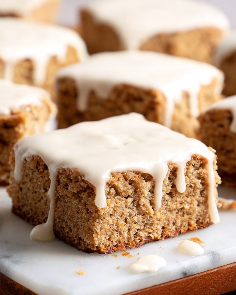 The image shows several square pieces of light brown cake with a rough, crumbly texture on a white marbled surface. Each piece is topped with a thick layer of creamy white icing that drips down the sides in uneven streams, creating a smooth contrast to the cake's coarse surface. The cake squares are arranged closely together, some slightly overlapping, and the background remains softly blurred, keeping the focus on the textured cake and smooth icing. Photo taken with an iphone --ar 4:5 --v 7