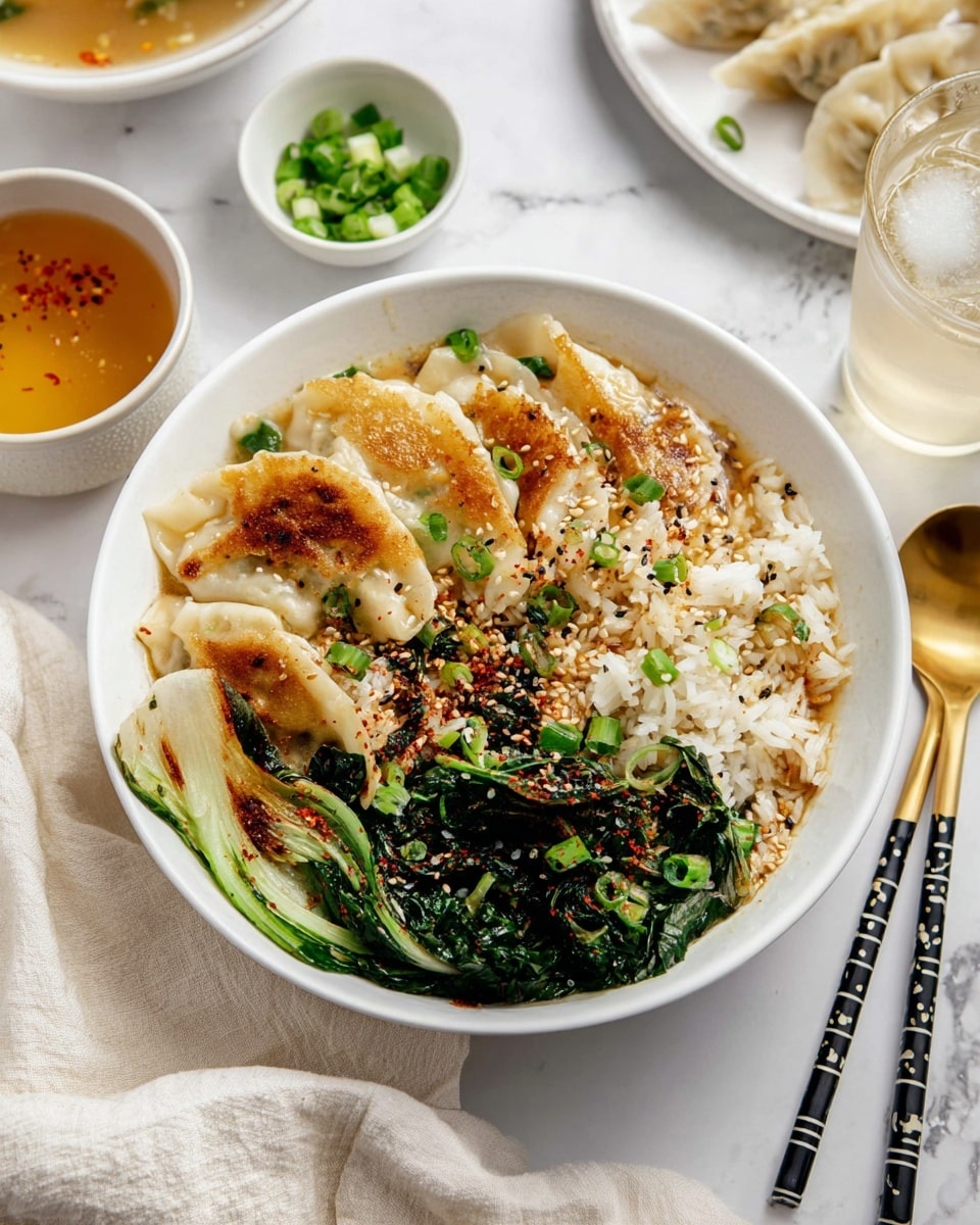 A white bowl filled with a layered dish showing pan-fried dumplings with golden brown crisp spots on top, resting on white rice sprinkled with sesame seeds and chopped green onions; on one side of the bowl there are bright green cooked leafy vegetables with some chili flakes and sesame seeds sprinkled over them. The bowl is placed on a white marbled surface surrounded by a glass of water with ice, a plate of more dumplings, a small white bowl of chopped green onions, black chopsticks with white stripes, and a bowl of clear broth. A golden spoon lays on a cream cloth in the background. photo taken with an iphone --ar 4:5 --v 7