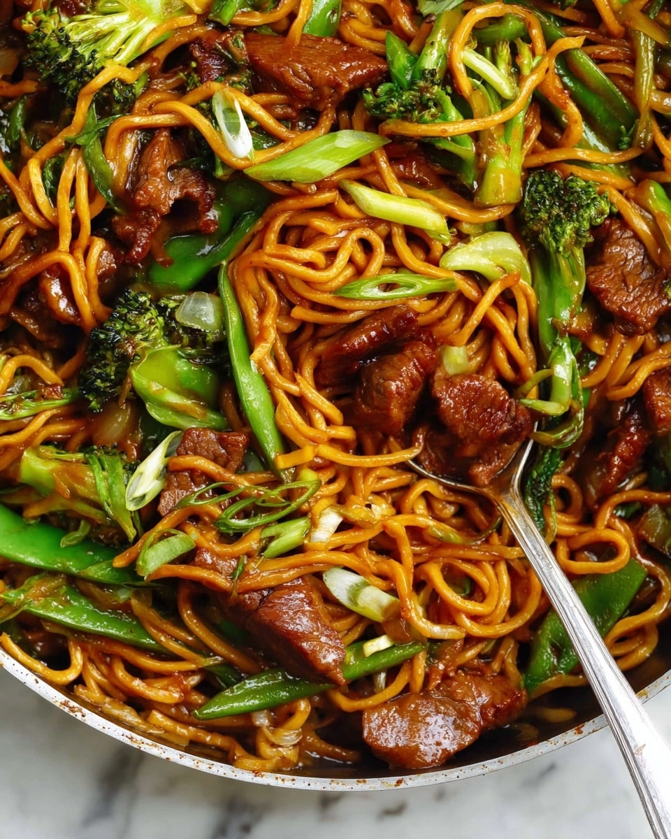 A close-up view of a dish with three main layers: long, thin orange noodles twisted and tangled throughout the image as the base layer; on top of the noodles, there are many pieces of browned meat with a slightly crispy texture; scattered among the noodles and meat are bright green vegetables including broccoli florets, snap peas, and chopped green onions. The food is glossy with a rich brown sauce coating everything, and a silver spoon is placed on the right side, scooping some noodles, meat, and vegetables. The background is a white marbled texture. photo taken with an iphone --ar 4:5 --v 7