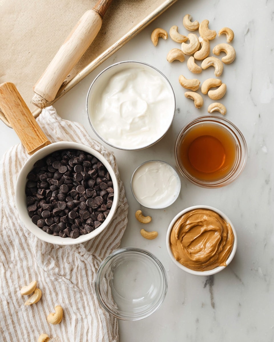 The image shows an overhead view of several small white bowls and a white saucepan with a light wooden handle, all placed on a white marbled surface. One white bowl contains smooth white yogurt, positioned near the top center. To its right, a small white bowl holds a light brown liquid, and below that, there is a small clear bowl with white solid coconut oil. At the bottom right, a clear bowl contains a creamy tan nut butter, with a smaller clear bowl beside it holding chopped nuts. The white saucepan at the bottom left is filled with shiny dark chocolate chips. Scattered around the bowls are whole cashew nuts, and part of a striped cloth in beige and white stripes is visible under the pan. A corner of a parchment-lined baking sheet is seen at the top left. Photo taken with an iphone --ar 4:5 --v 7