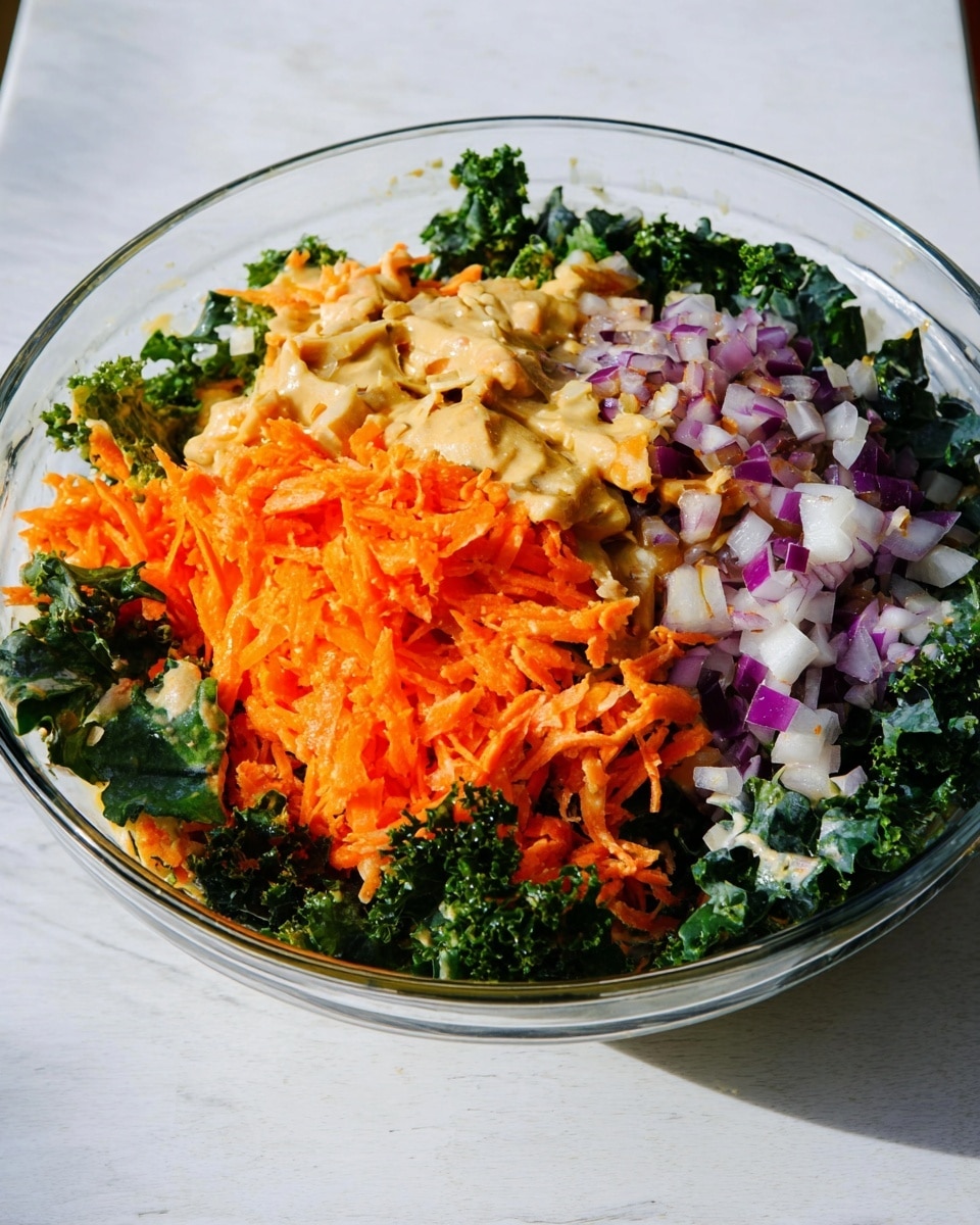 A clear glass bowl sits on a white marbled surface, filled with three main layers of salad ingredients. The bottom layer consists of dark green, curly kale leaves, some of which have a creamy tan dressing drizzled on top. Above the kale, there is a bright orange layer of finely shredded carrots, piled thickly in the center and slightly spreading out. To the right of the carrots, there is a chunky layer of diced purple and white onions, also topped with the same tan dressing. The dish is rich in color contrast and texture, with the creamy dressing adding a glossy finish. Photo taken with an iphone --ar 4:5 --v 7