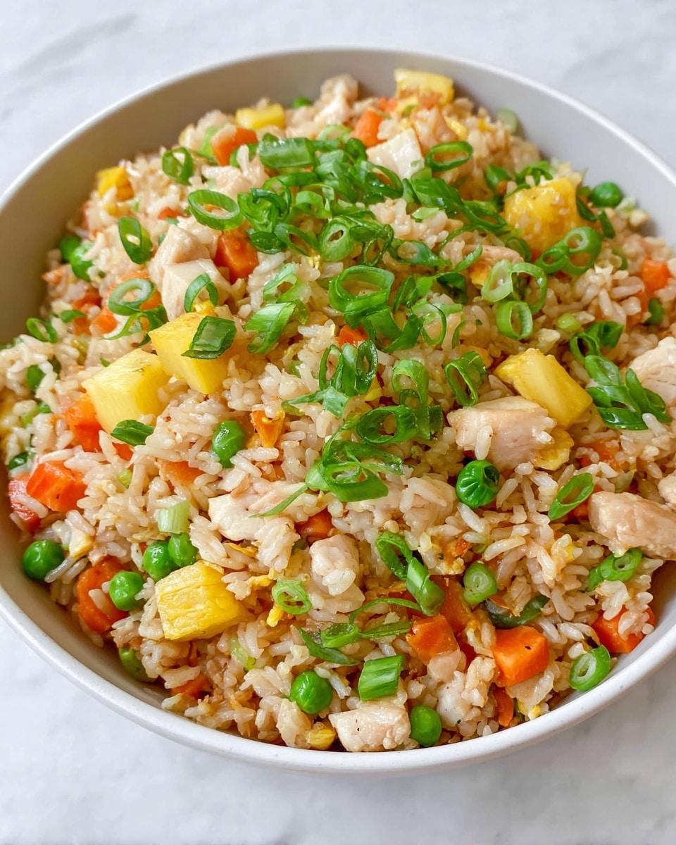A white bowl filled with fried rice showing three main layers: the base layer of light brown cooked rice mixed with small cubes of yellow pineapple and orange carrots; scattered throughout are bright green peas and soft white chicken pieces; the top layer is garnished with thin slices of fresh green onions spread evenly across the surface. The texture looks light and fluffy, sitting on a white marbled surface. photo taken with an iphone --ar 4:5 --v 7