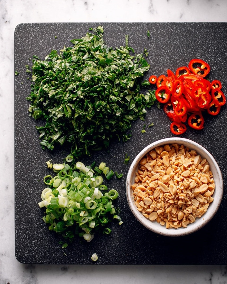 The image shows a dark textured board on a white marbled surface, with three piles and one bowl of chopped ingredients arranged neatly. At the top left is a large pile of finely chopped green herbs with a leafy texture. Below it, there is a smaller pile of sliced green onions with a tubular shape and a fresh look. On the top right, a pile of thin, bright red chili rings with some seeds visible is placed. To the bottom right, a white bowl filled with light brown crushed peanuts, showing a rough, crunchy texture, rests on the board. Photo taken with an iphone --ar 4:5 --v 7