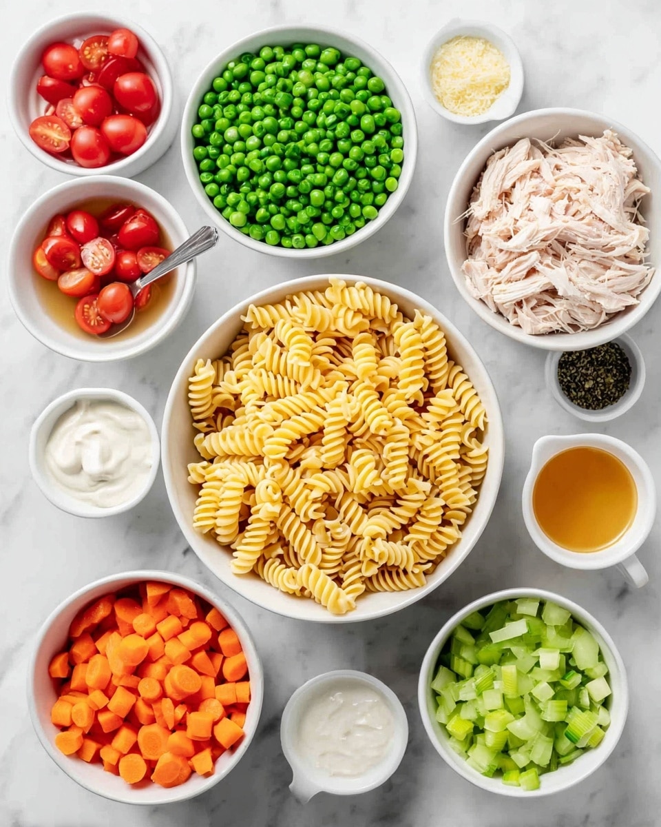 A top view of multiple white bowls arranged on a white marbled surface, each holding different ingredients. The largest bowl in the center contains yellow dry spiral pasta. Above it, a medium bowl is full of bright green frozen peas with a lightly frosted texture. To the right, another medium white bowl holds shredded light pink cooked chicken with a fork inside. Below this, a bowl is filled with diced bright orange carrots. Under the carrots, a bowl contains chopped pale green celery pieces. To the left of the pasta, a bowl with halved red cherry tomatoes. Surrounding these are small white bowls holding minced garlic, an orange liquid (possibly sauce), salt and pepper, creamy white mayo, light beige dressing, white sour cream, and finely chopped green herbs. photo taken with an iphone --ar 4:5 --v 7