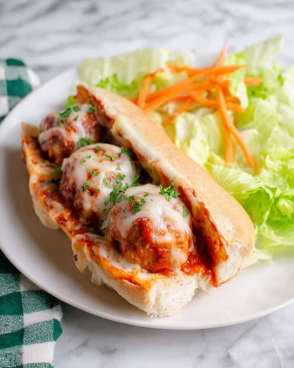 A white sandwich roll is filled with three meatballs covered in red tomato sauce and melted white cheese, sprinkled with green parsley. The sandwich sits slightly open, showing the pizza-style filling inside. It is placed on a white plate with some light green lettuce salad with thin orange carrot strips on the side. There is a white marbled surface underneath and a green and white checkered cloth near the plate. photo taken with an iphone --ar 4:5 --v 7