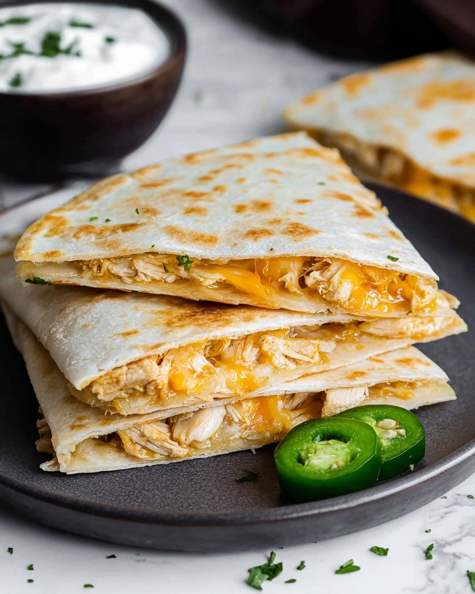 The image shows a stack of three folded triangle quesadilla slices on a white plate, each slice revealing two layers of light golden brown toasted tortilla with melted orange cheese and light beige cooked chicken pieces inside. The quesadilla edges show a slight crisp texture, and one green sliced jalapeño with seeds is placed near the bottom right corner of the plate. The plate sits on a white marbled surface with small green herb bits scattered around. In the background, there is a dark bowl filled with creamy white sour cream topped with small chopped herbs. photo taken with an iphone --ar 4:5 --v 7