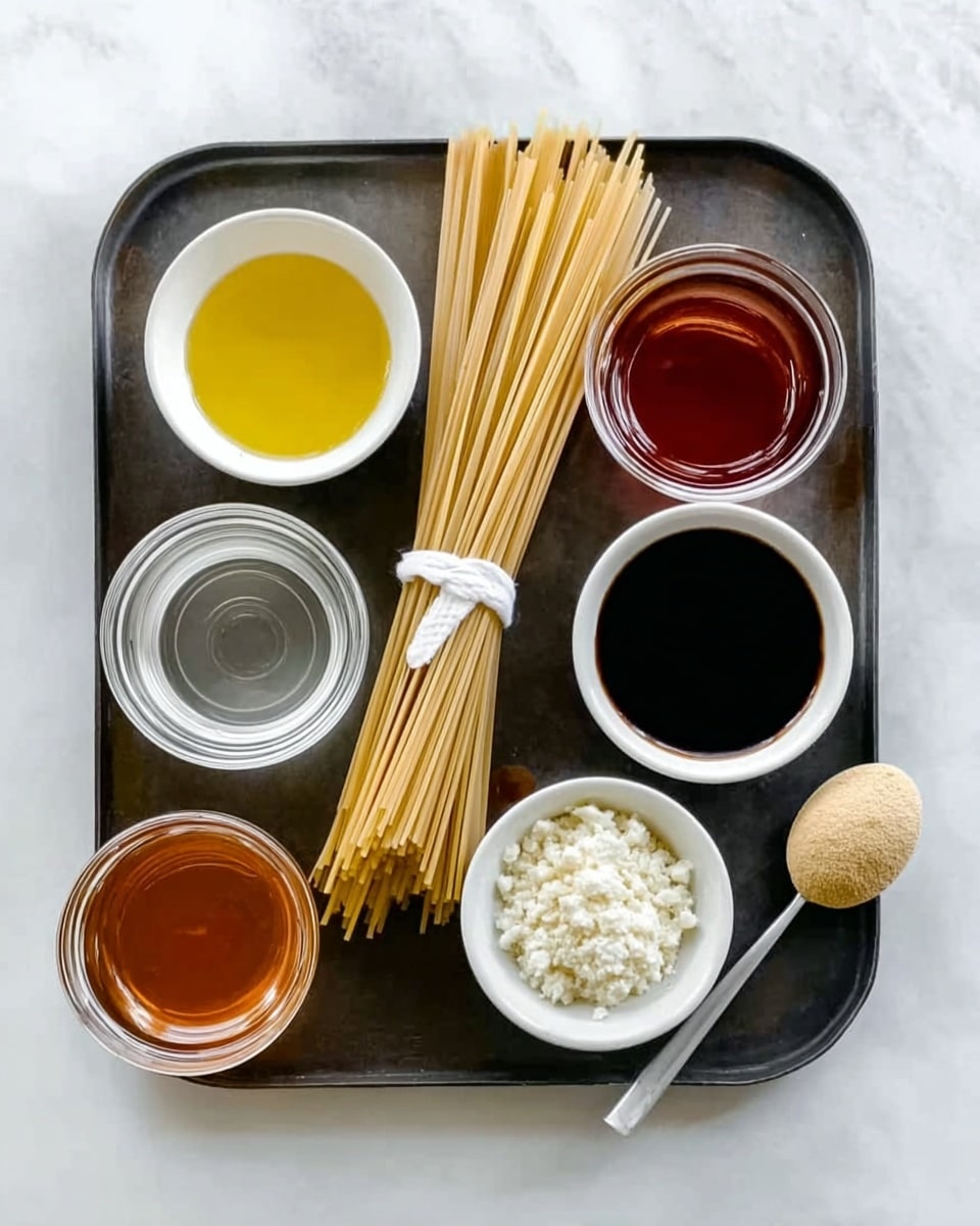 The image shows a dark metal tray with several small white bowls placed on it, each holding different ingredients. The tray's center has a bundle of uncooked spaghetti tied with a white string. Starting from the top left, there is a small white bowl filled with yellow oil, next to it a glass bowl with dark red sauce, and below that a white bowl with white crumbly cheese. In the middle row on the left is a white bowl with clear liquid, and to the right is a glass bowl with a dark brown sauce. Below these, a small glass container with amber sauce is on the left, a white bowl with a creamy beige powder is in the middle, and a small spoon with a light yellow paste rests on the tray on the right. The tray sits on a white marbled surface. Photo taken with an iphone --ar 4:5 --v 7