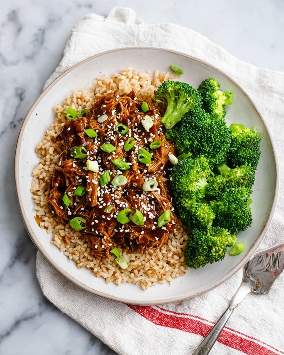 A white plate holds a meal with three main layers. The first layer is a bed of light brown rice spread evenly across the plate. On top of the rice, there is a thick layer of shredded meat coated in a glossy, dark brown sauce, sprinkled with white sesame seeds and small slices of green onions. On the right side of the plate, bright green steamed broccoli florets add a fresh, textured contrast to the meal. The plate is placed on a white marbled surface with a white cloth that has a red stripe underneath it, and a silver fork rests beside the plate. photo taken with an iphone --ar 4:5 --v 7