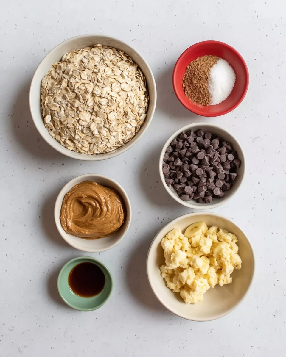 The image shows six small white bowls and one small red bowl arranged on a white marbled surface. The largest white bowl near the center is full of pale rolled oats with a dry, rough texture. Below it is another white bowl filled with many small, dark chocolate chips that have a smooth, glossy finish. To the right is a white bowl with mashed yellow bananas, showing a soft and uneven texture. Above the oat bowl is a small two-color bowl with brown and white powders, the brown having a grainy texture and the white powder fine and smooth. Close to that is a small red bowl that is empty with a smooth glossy surface. At the bottom center is a tiny green bowl holding a dark brown liquid with a shiny, smooth texture. To the left is a small white bowl with a large dollop of light brown peanut butter showing a thick, creamy texture. photo taken with an iphone --ar 4:5 --v 7