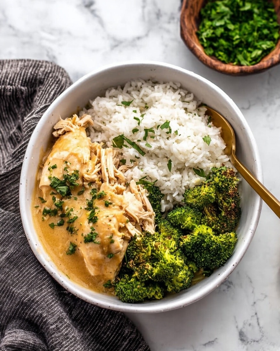 A white bowl sits on a white marbled surface filled with three main parts: at the bottom and covering half the bowl is a layer of plain white rice with a slightly fluffy texture, on the right side is a group of bright green broccoli pieces with some crispy dark spots, and on the left side is a cooked chicken piece covered with a smooth light brown sauce, with some shredded chicken underneath the sauce. In the chicken and rice area, light green herb bits are sprinkled on top. A gold spoon rests inside the bowl, partly lifting the shredded chicken. Nearby, there is a brown bowl filled with green chopped herbs and a dark striped cloth. Photo taken with an iphone --ar 4:5 --v 7
