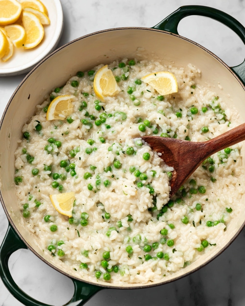 A large white pot with dark green handles filled with creamy risotto mixed with bright green peas evenly spread throughout. On the right side inside the pot are two small lemon wedges resting on top of the rice. A wooden spoon is scooping some of the risotto near the lemon wedges. In the background on the left side, there is a small white plate holding additional lemon wedges on a white marbled surface. The rice has a soft, slightly shiny texture, and the peas add a pop of green color that contrasts with the creamy white base. photo taken with an iphone --ar 4:5 --v 7