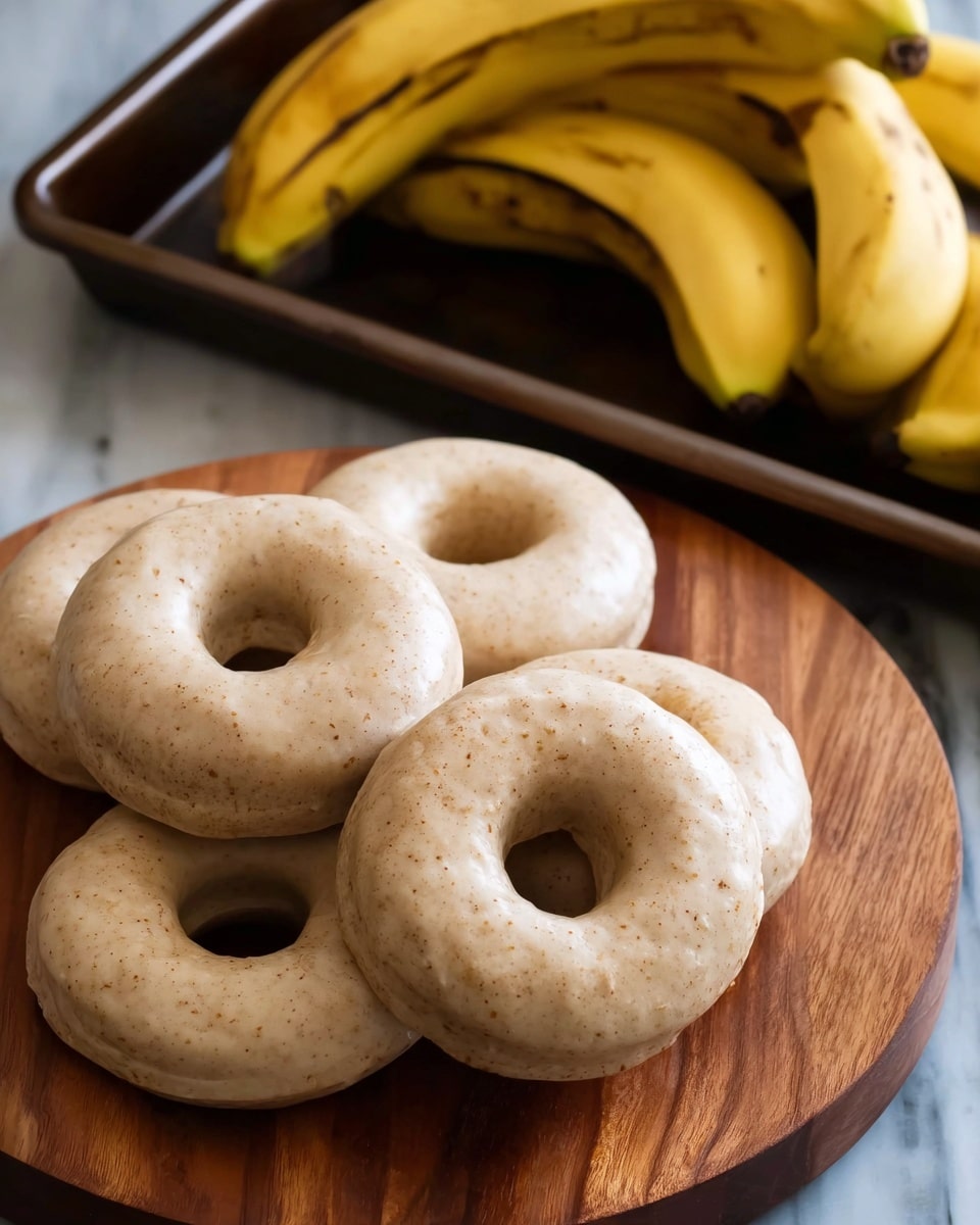 The image shows five raw doughnuts placed on a round wooden board. They have a light beige color with small brown specks and a smooth, slightly shiny surface. Each doughnut has a hole in the center and they're arranged in a loose cluster with some slightly touching. Behind the board, there are three yellow bananas with some brown spots, placed on a tray with a dark metal frame. The background surface is replaced with a white marbled texture. Photo taken with an iphone --ar 4:5 --v 7