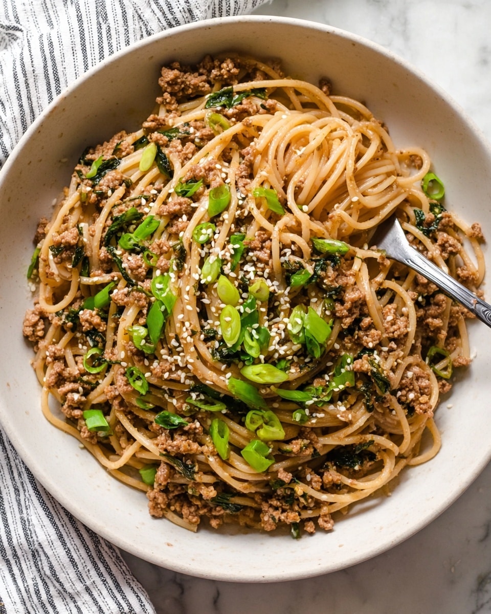 A white bowl filled with light brown spaghetti mixed with small pieces of cooked ground meat and dark green chopped herbs, topped with bright green sliced spring onions and sprinkled with white sesame seeds. A silver fork is placed on the right side inside the bowl, slightly lifting some noodles. The bowl is set on a white marbled surface with a striped cloth partially visible in the top left corner. photo taken with an iphone --ar 4:5 --v 7